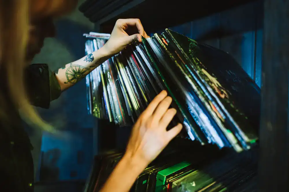 Hands flipping through vinyl records in a dimly lit shop