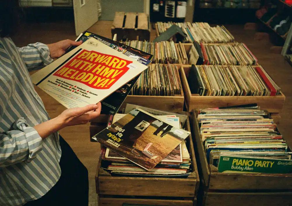 Customer carefully flipping through vinyl records in a wooden crate