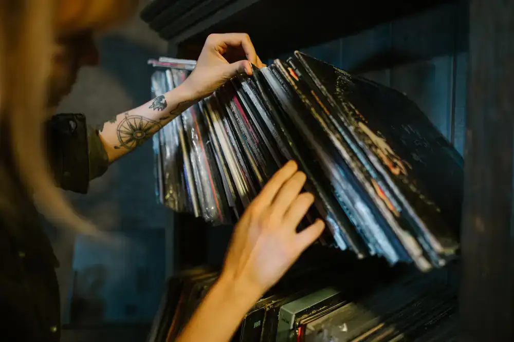 Hands browsing through a stack of slightly worn vintage record sleeves